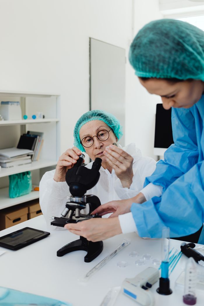 The Art of Drawing Readers In: Your attractive post title goes here Researchers using microscope in a medical lab setting, equipped with protective gear and scientific tools.